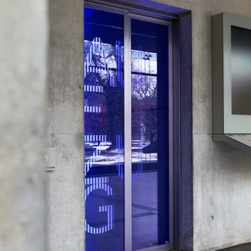 Teleskopschiebetüre mit bedrucktem Glas und blauer Lichtreflektion - Aufzug der Firma Butz und Neumair in der Architektenkammer in München